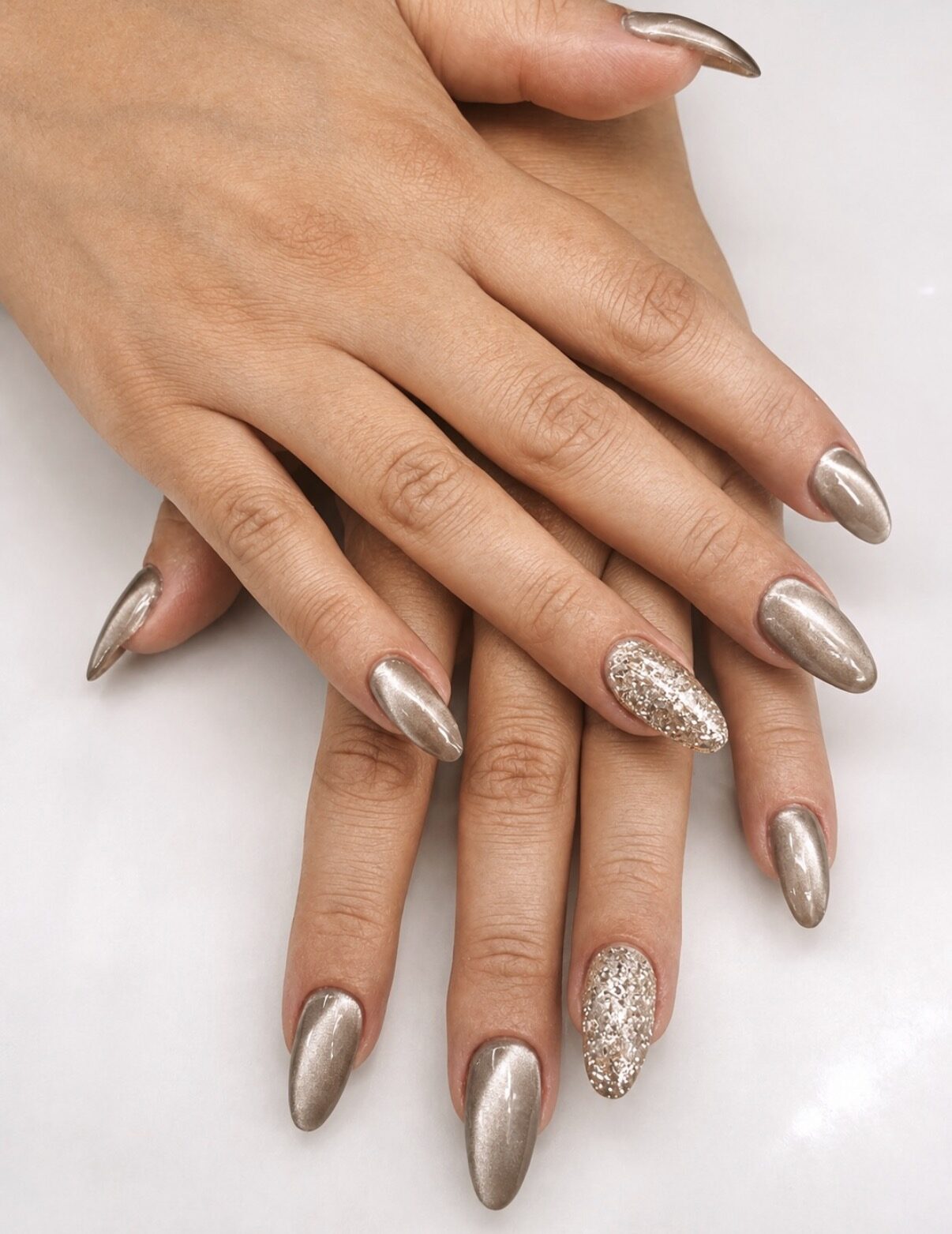 Ongles amande longs en chrome champagne doré, deux ongles pailletés en rappel.