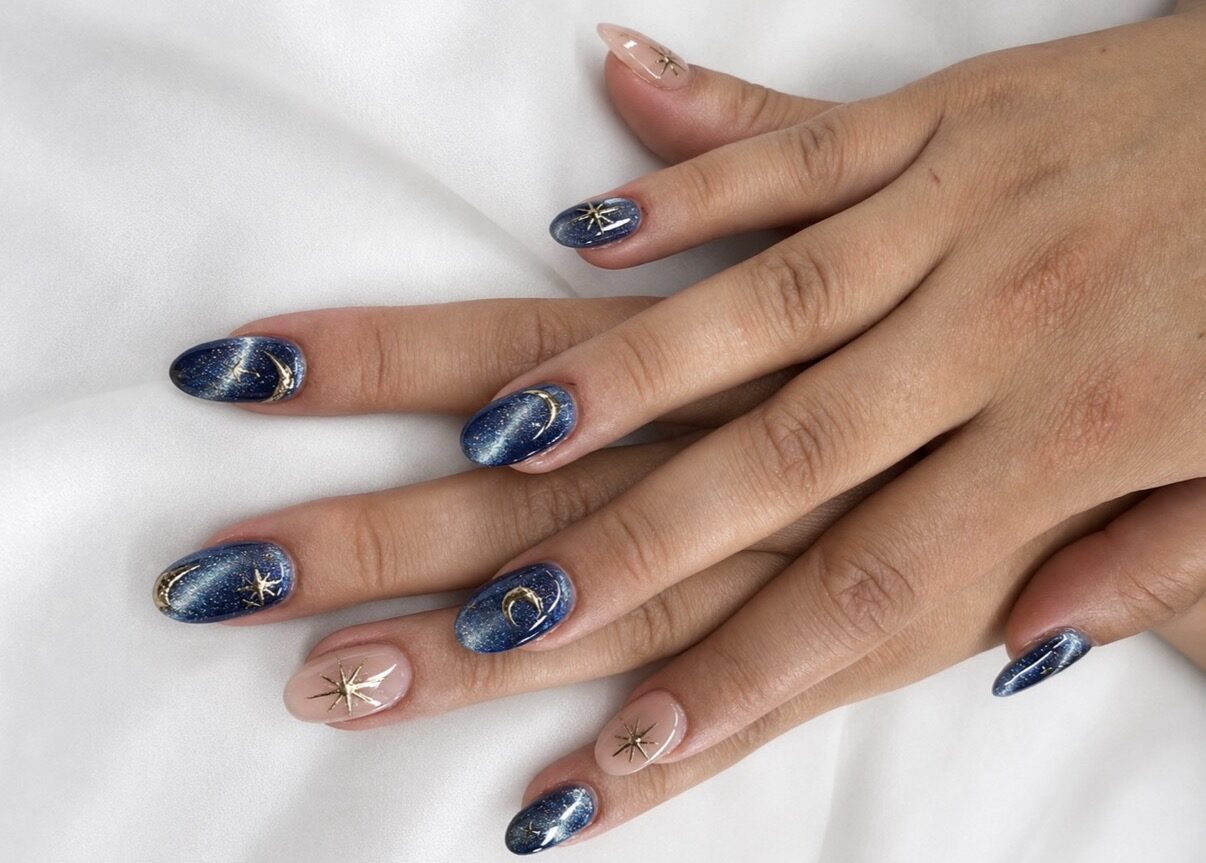 Nail art : fond bleu nuit marbré, étoiles et croissants dorés peints à la main.