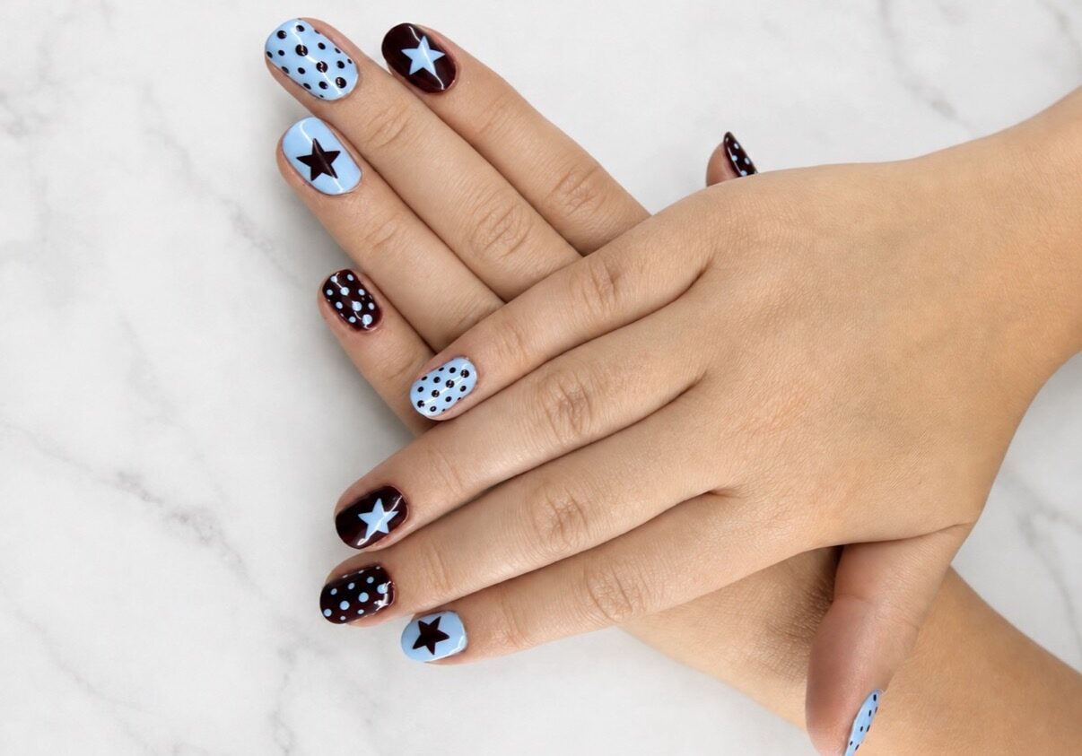 Nail art bleu ciel et noir : étoiles, pois et aplats alternés.