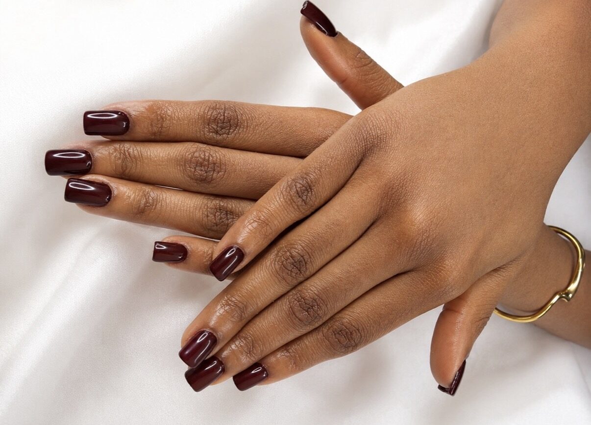 Ongles longs carrés bordeaux chocolat, sur drapé blanc.